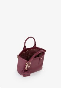 Bolso tote de cuero burdeos con dos asas superiores, herrajes en tono dorado y una etiqueta removible, que cuenta con un bolsillo interior con cremallera y forro de tela.