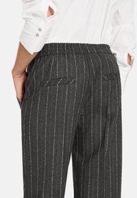 Gray pinstripe trousers with an elastic waist, two back pockets, and a textured fabric. The waistband is gathered for comfort.