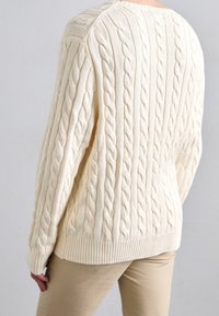 Kremowy sweter w splot sznurkowy, charakteryzujący się teksturowanym wzorem, ściągaczami na mankietach i dole oraz luźnym krojem. Posiada klasyczny okrągły dekolt.
