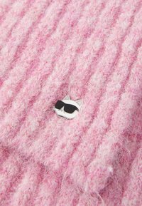 Pink textured fabric with a ribbed pattern, featuring a silver cat pin with black sunglasses attached to the center.