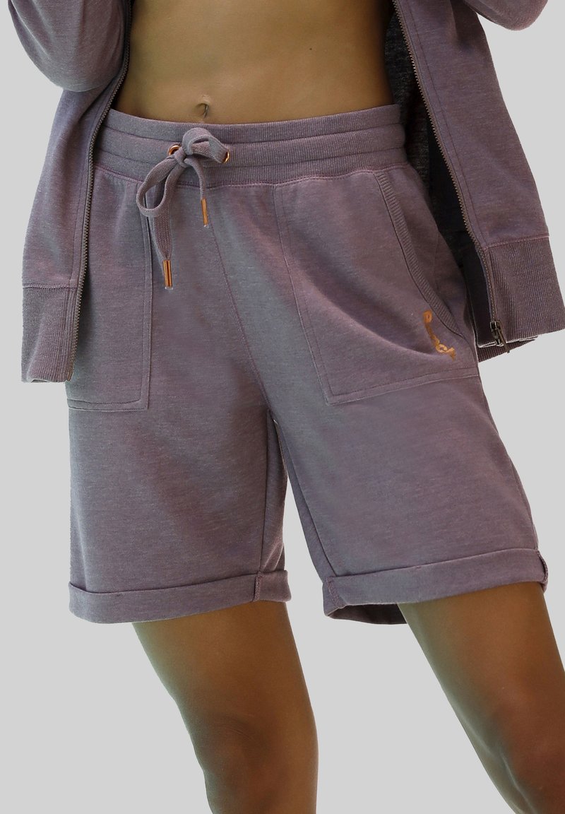 Bermuda in cotone viola chiaro con vita regolabile tramite coulisse, due tasche anteriori e orli arrotolati. Dettagli in oro sulla coulisse e sul logo.