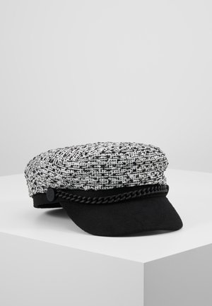 Zwart-witte textuurrijke bakkerboypet met een zwarte gevlochten rand en een korte afgeronde klep, geplaatst op een wit oppervlak.