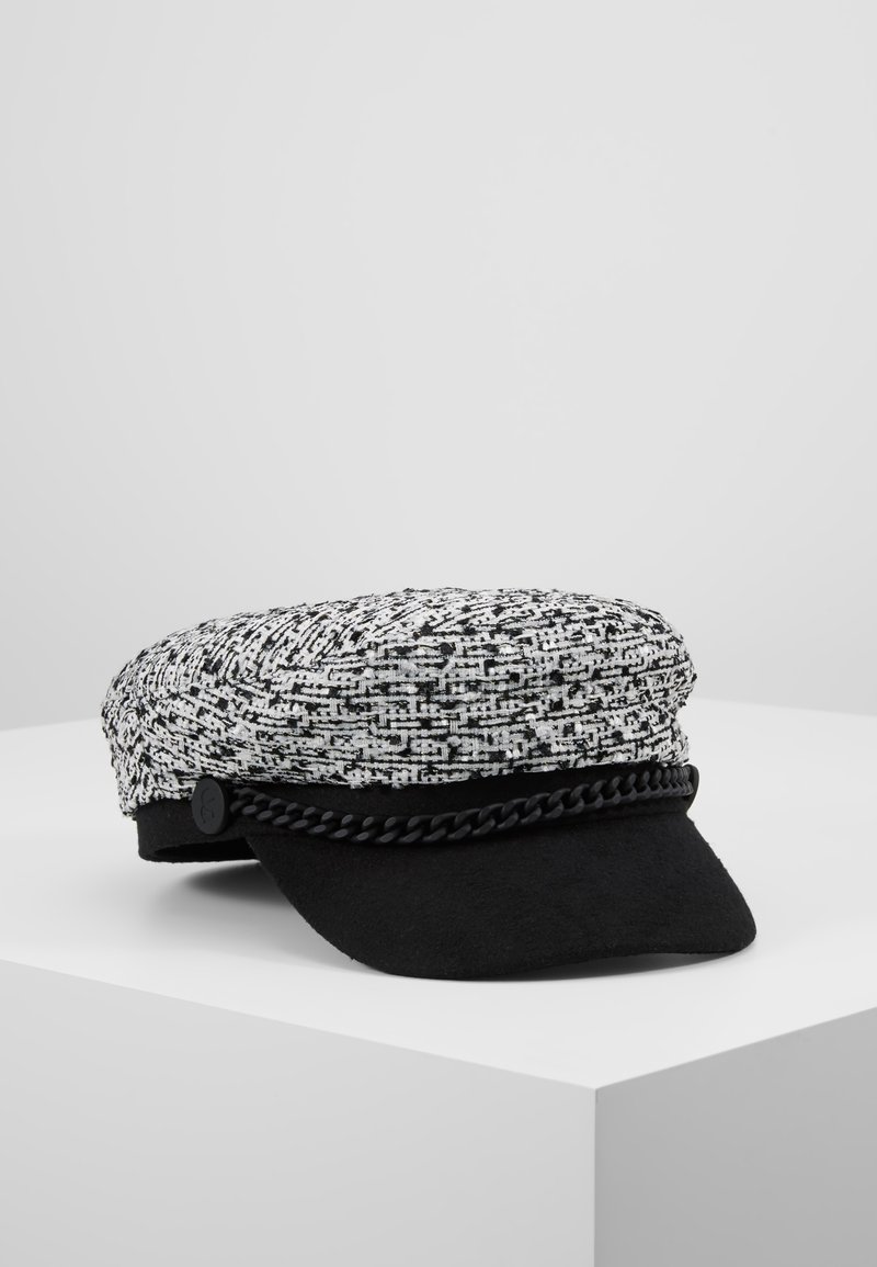 Casquette gavroche texturée en noir et blanc avec une bordure tressée noire et une visière courte et arrondie, posée sur une surface blanche.