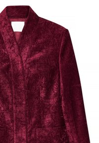 Kruvinės aksominės švarkas su šališku apykakle, dviem priekinėmis kišenėmis ir tekstūruotu paviršiumi. Audinys turi turtingą, blizgantį blizgesį.