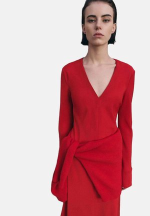Vestido rojo de manga larga, escote en V y detalle de drapeado en la cintura. Confeccionado en una tela suave con textura delicada.
