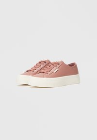 Pink canvas sneakers with a thick white sole, rounded toe, and lace-up front. Features minimal branding on the side.