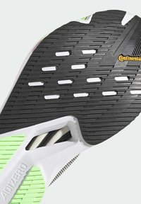 Semelle extérieure texturée en noir et blanc avec des accents verts, présentant une surface à motif et des perforations pour l'adhérence. Logo "Continental" présent.