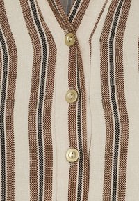 Stribet top med tan-, brun- og sorte linjer; blødt stof med tekstureret finish; seks gyldne knapper foran.