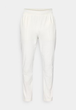 White, lightweight, tapered pants with an elastic waistband and side pockets; smooth texture with minimal creasing.