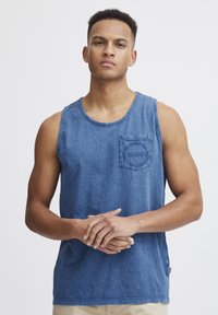 Blå denim tanktop med rund halsutskjæring og en venstre brystlomme som viser teksten "BLEND". Løs passform, myk tekstur og uformelt design.