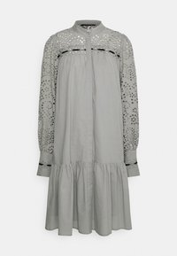 Vestido gris claro con botones en el frente y una falda de capas. Presenta bordados y detalles recortados en las mangas largas. Textura de tela suave.