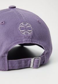 Purple cotton baseball cap with a fabric strap and metal buckle. Features an embroidered logo on the back and a rounded crown.
