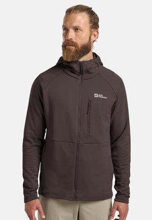 Giacca marrone con cappuccio, realizzata in tessuto strutturato, zip frontale completa e taschino verticale sul petto. Presenta un logo sul lato sinistro del petto.