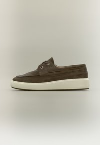 Καφέ καστόρινο casual παπούτσι με χοντρή λευκή σόλα, κορδόνια στο μπροστινό μέρος και ραφές moc toe, παρουσιασμένο σε ουδέτερο φόντο.