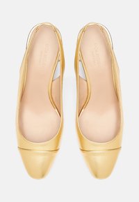 Ballerines en cuir doré avec une découpe arrière et un bout carré, avec des semelles intérieures beiges, vues de dessus sur un fond blanc.