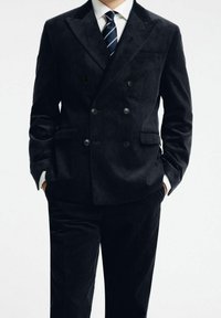 Dubbelknäppt kordflöjlsblazer i mörk marinblå färg, med en texturerad tyg, slagkragar, två framfickor och matchande byxor.