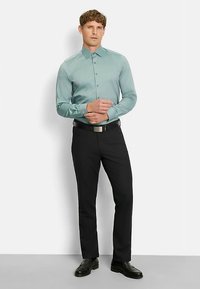 Hellblaues Hemd mit Kragen und langen Ärmeln, kombiniert mit schwarzen Hosen und eleganten Schuhen; glatte Textur, tailliertes Design.