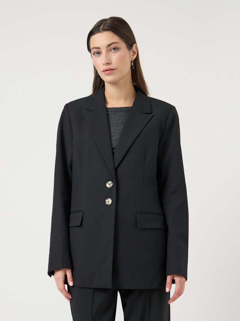 Μαύρο σακάκι με άνετη εφαρμογή, διαθέτει δύο μπροστινές τσέπες, ασημένια κουμπιά και γιακά με σχισμή. Ύφασμα λείο με ματ φινίρισμα.