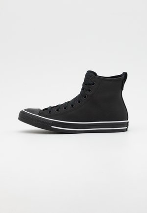 Czarny wysoki sneaker z czarnymi sznurówkami, czarną podeszwą i białym paskiem, pokazany z profilu na jednolitym białym tle.