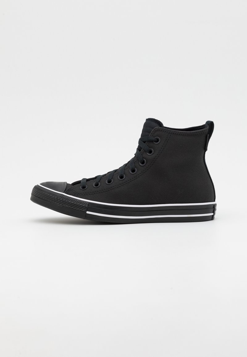 Basket montante noire avec lacets noirs, semelle noire et détail bande blanche, présentée de profil sur fond blanc uni.