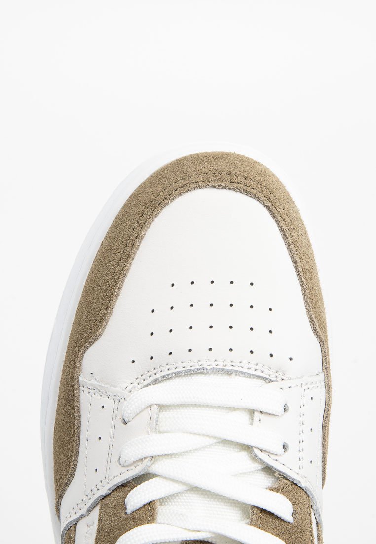 Weiße und beige Sneaker mit einer glatten Lederzehe und Wildleder-Akzenten. Hat Perforationen für Atmungsaktivität und flache weiße Schnürsenkel.