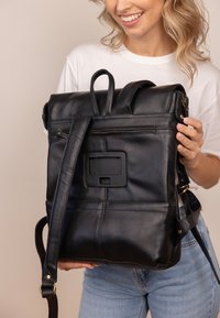 Black leather backpack with a roll-top design, adjustable straps, exterior zip pocket, and decorative panel on the back. Smooth texture.