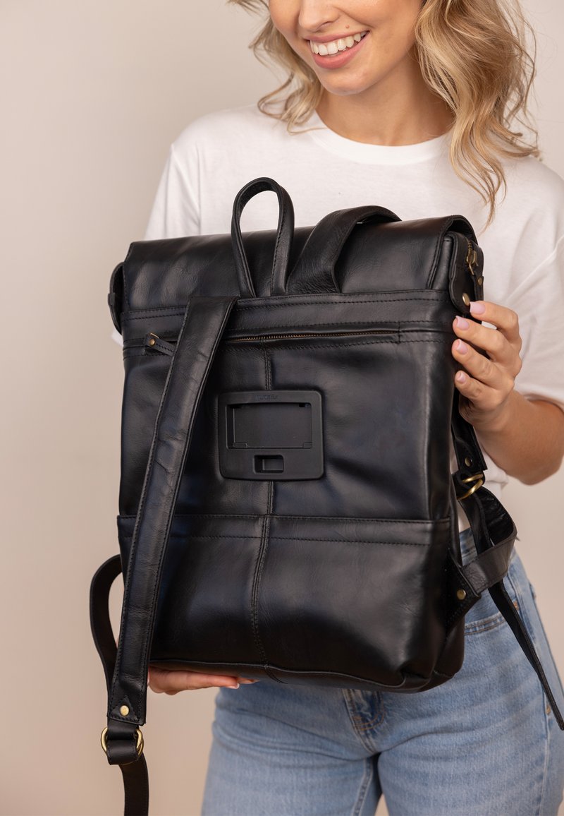 Black leather backpack with a roll-top design, adjustable straps, exterior zip pocket, and decorative panel on the back. Smooth texture.