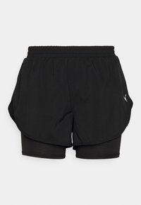 Pantalones cortos deportivos negros con una capa exterior ligera y pantalones interiores ajustados. Presentan un diseño texturizado y una cintura elástica.