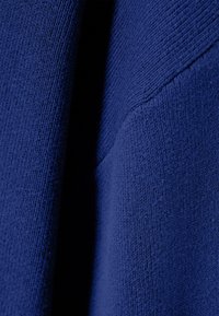 Tissu bleu texturé, tissé de près avec un motif côtelé. Matériau doux, légèrement extensible, présentant une finition lisse et un subtil éclat.