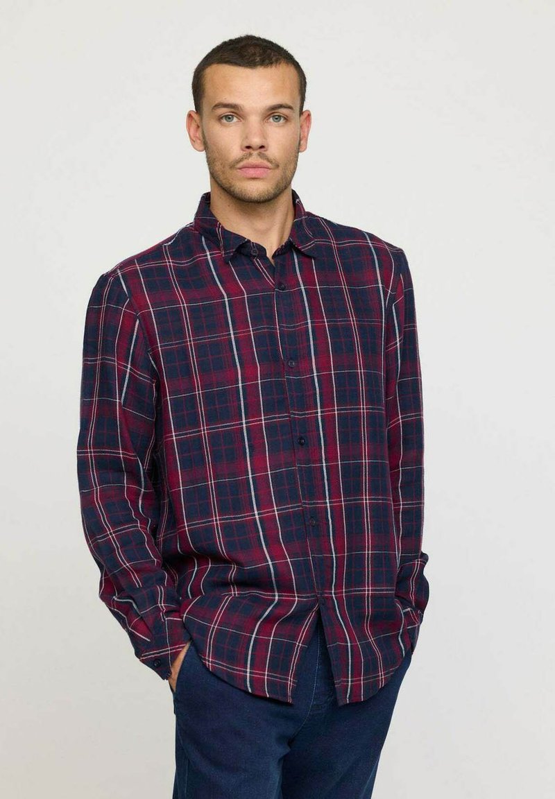 Chemise en flanelle à carreaux navy et bordeaux avec des accents blancs, fermeture à boutons sur le devant, manches longues et coupe décontractée. Tissu texturé.