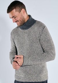 Strickpullover mit einem hohen, strukturierten grauen Kragen und einem karierten Muster in cremigen und grauen Tönen. Verfügt über gerippte Bündchen und Saum.