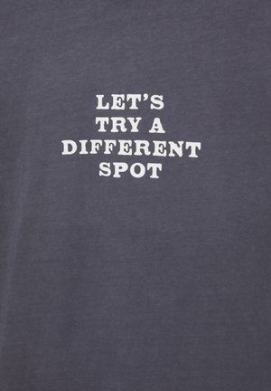 White text reading "LET'S TRY A DIFFERENT SPOT" on a plain dark gray fabric background.