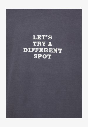 White text reading "LET'S TRY A DIFFERENT SPOT" on a plain dark gray fabric background.