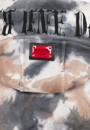 Batiked Hoodie in Grau-, Beige- und Cremetönen. Schwarzer Text auf der Vorderseite und ein rotes Logotag mit metallischen Akzenten am Hals. Weiche Textur.