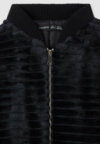 Giacca bomber nera in tessuto testurizzato a coste, con chiusura a zip, colletto a coste e fodera nera uniforme. Etichetta di dimensione inclusa.