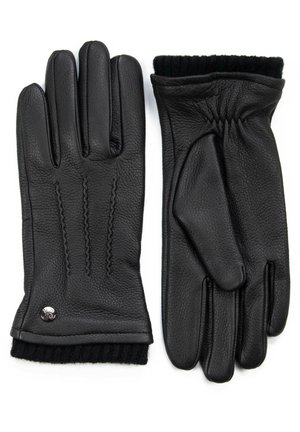 Schwarze Lederhandschuhe mit drei genähten Akzenten auf der Rückseite, gerippter schwarzer Strickbund und einem silbernen Logodetail am Handgelenk.
