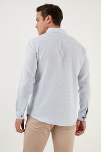 Lichtblauw languithemd in een gestructureerde stof, met een button-down kraag en verstelbare manchetten met zwarte knopen.