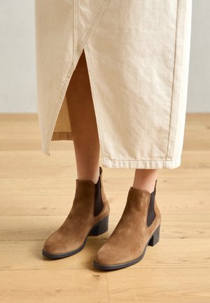 Brune semsket chelseaboots med en kraftig svart hæl, som har elastiske sidepaneler og en glatt teksturert finish.