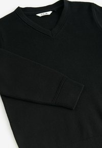Maglione nero a maglia con scollatura a V, polsini e orlo a costine. Tessuto morbido senza motivi o dettagli in vista. Etichetta del marchio visibile all'interno del colletto.