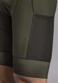 Athletic shorts in dark olive green, made from stretchy fabric, featuring mesh paneling and flatlock seams with "BIORACER" branding.