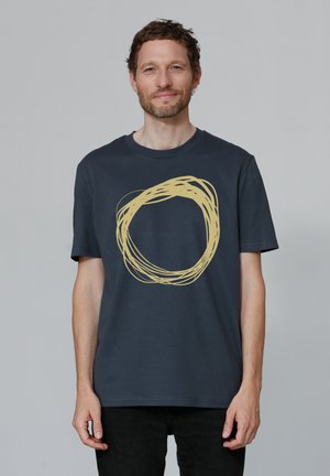 Marineblauwe t-shirt van katoen. Het heeft een groot, cirkelvormig gele ontwerp in het midden, met een zachte, gladde textuur en korte mouwen.