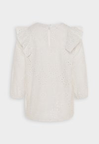 Blusa bianca con maniche a volant, caratterizzata da motivi ad occhio ricamati. Presenta una chiusura a fessura sul retro e maniche lunghe. Tessuto morbido.