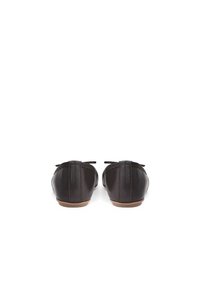 Hnědé kožené baleríny s kulatou špičkou, měkkou texturou a malou mašlí na zadní straně. Ploché podrážky s minimálním vzorkem.