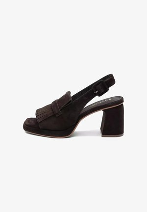 Damski but typu slingback z ciemnobrązowego zamszu z blokowym obcasem, frędzlową przednią klapką oraz regulowanym paskiem z klamrą na białym tle.