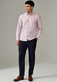 Camicia a maniche lunghe rosa con motivo, colletto a punta, abbinata a pantaloni scuri e scarpe stringate marroni, con una texture liscia.