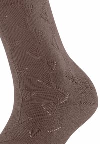 Brązowa dziergana skarpeta z teksturowanym wzorem w kształcie strzałek, gładkim wykończeniem i lekko prążkowanym mankietem dla dodatkowego detalu.