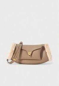 Barna bőrből készült kézitáska puha, krémszínű szőrmével díszítve. Arany színű kapoccsal és állítható pánttal rendelkezik. Kerekded formájú, texturált felülettel.