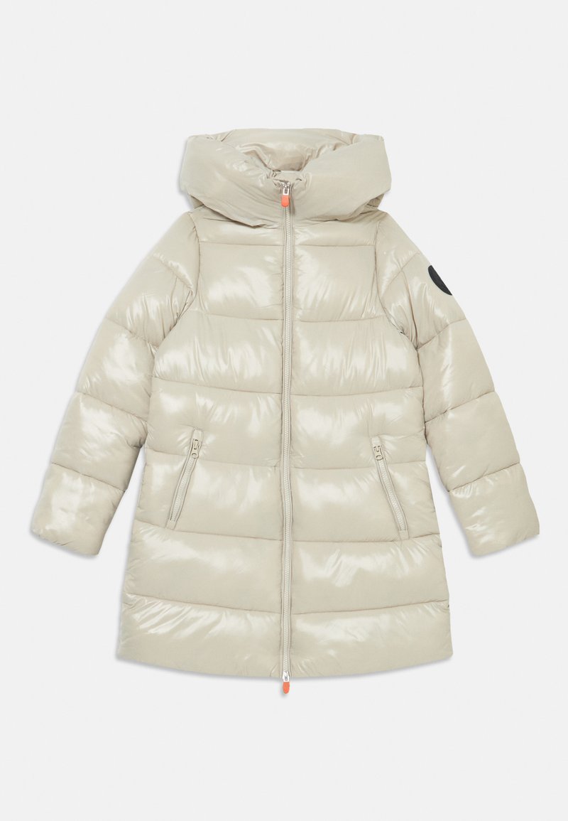 Šviesiai rudas pūkų paltas su blizgiu paviršiumi, gobtuvu, dviem užtrauktuku užsegamomis šoninėmis kišenėmis ir kontrastingu juodu pleistru ant vieno rankovės.