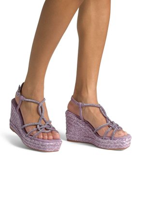 Sandali con tacco a cuneo lilla caratterizzati da una base in rafia intrecciata, un design del cinturino texturizzato con accenti metallici e uno stile open-toe.