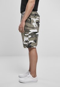 Cargo shorts dengan pola kamuflase yang menampilkan nuansa zaitun, abu-abu, dan putih. Terbuat dari kain bertekstur dengan saku samping dan potongan santai.